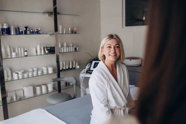 Foto retrato de una clienta con bata blanca en una esteticista