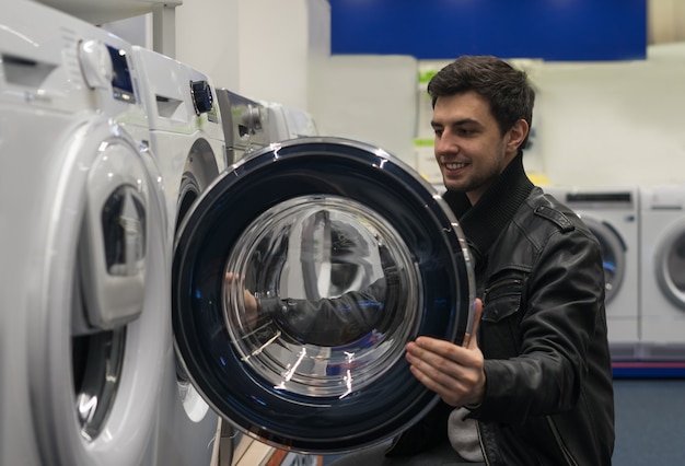 Retrato de cliente masculino eligiendo arandela en la tienda del supermercado. Abrió la tapa de la lavadora