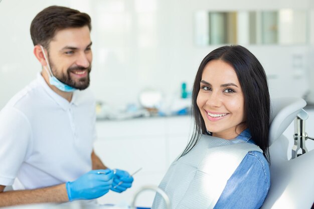 Retrato de cliente sonriente y dentista masculino en consultorio dental