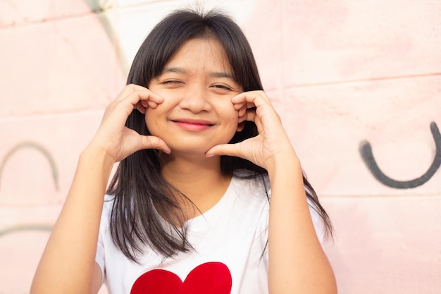 Retrato closeup cara joven asiática vistiendo camiseta con corazón sobre fondo de colores