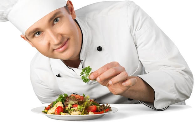 Retrato de un cocinero cocinero masculino preparando ensalada aislado sobre un fondo blanco.