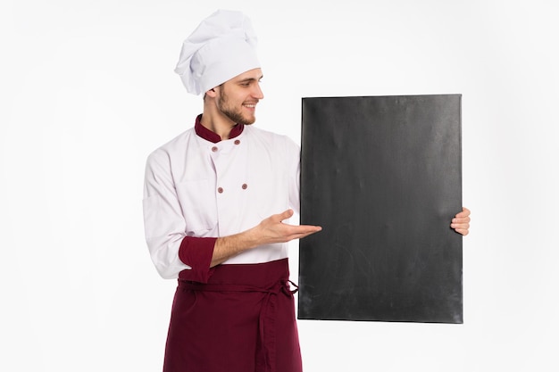 Retrato de un cocinero cocinero de sexo masculino alegre en uniforme que sostiene el tablero en blanco aislado en un fondo blanco.