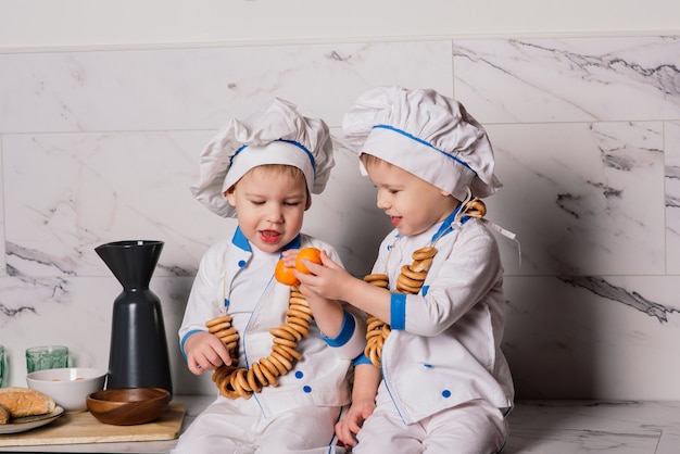 Retrato de un cocinero de niño pequeño con sartén en la cocina. Diferentes ocupaciones. Aislado sobre fondo blanco. Gemelos