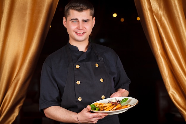 Retrato del cocinero de sexo masculino sonriente hermoso del cocinero en la situación uniforme