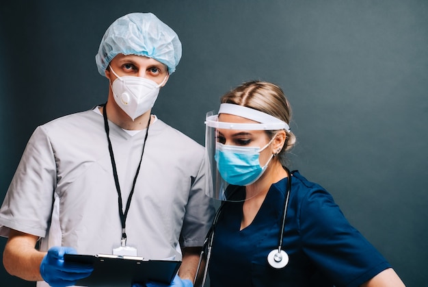 Retrato de colegas de enfermeras de trabajadores del hospital en máscaras protectoras médicas aisladas sobre fondo oscuro.