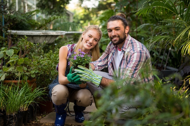 Retrato de colegas felices con plantas en macetas en el jardín