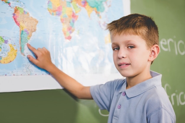 Retrato de colegial apuntando al mapa en el aula