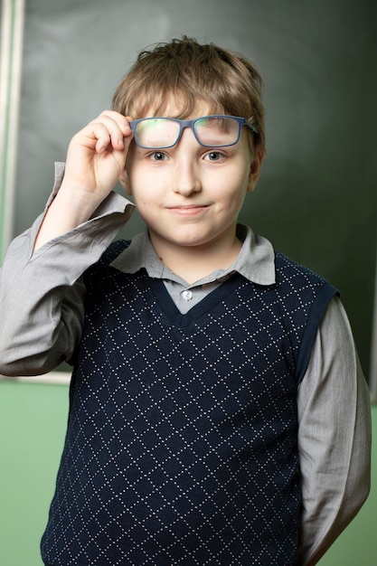 Retrato de un colegial divertido con gafas en la pizarra Estudiante de diez años en clase