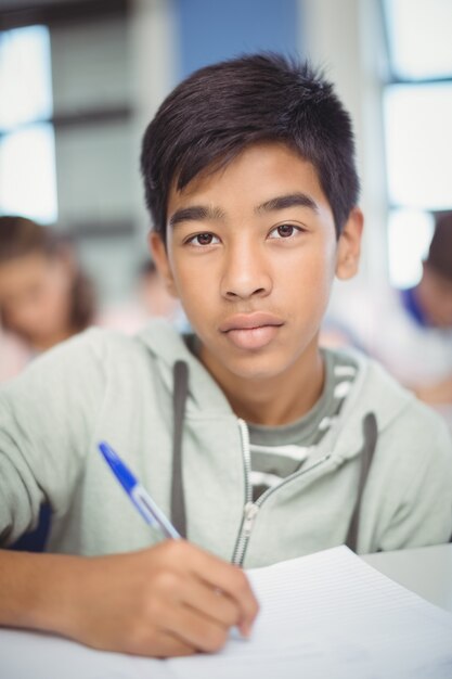 Retrato de colegial haciendo los deberes en el aula