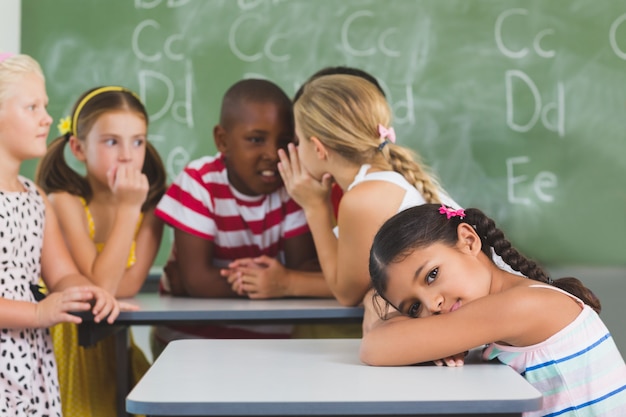 Retrato de colegiala acostada en el escritorio en el aula