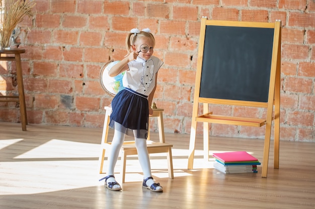 Retrato de colegiala caucásica con lupa si frente a su ojo, concepto de regreso a la escuela