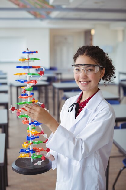 Retrato de colegiala feliz experimentando modelo de molécula en laboratorio