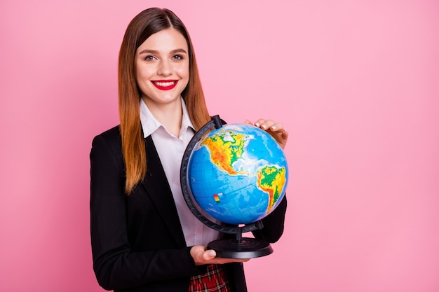 Retrato de colegiala inteligente nerd sosteniendo en manos globo aislado sobre fondo de color rosa