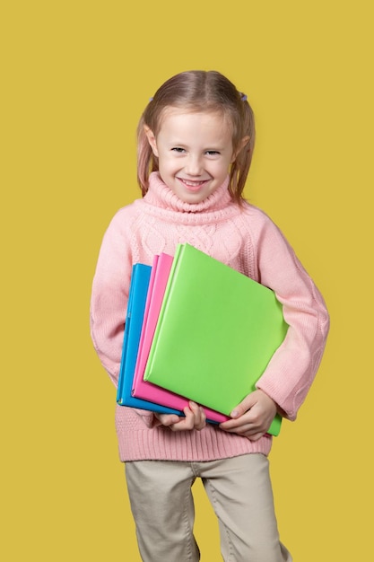 Retrato de colegiala con libros sobre fondo amarillo