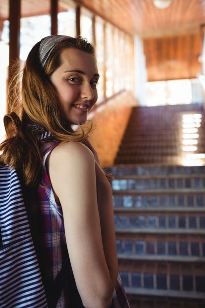 Retrato de colegiala a la mochila de pie junto a la escalera