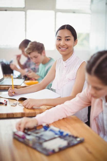 Retrato de colegiala sonriente haciendo los deberes en el aula