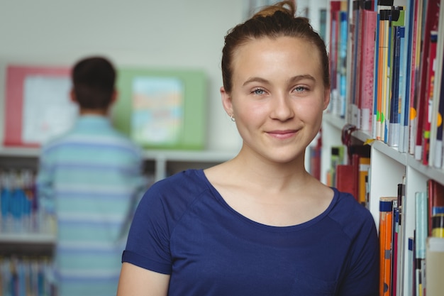 Retrato de colegiala sonriente sonriendo en la biblioteca