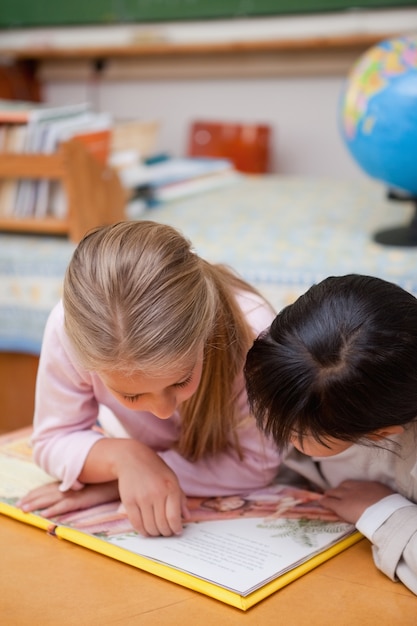 Retrato de colegialas enfocadas leyendo un cuento de hadas