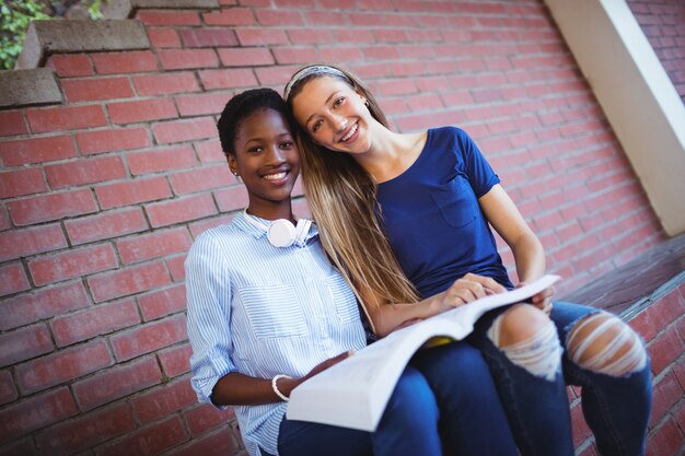 Retrato de colegialas felices leyendo libro