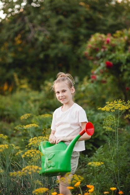 Retrato colorido de una niña preadolescente con una regadera en el jardín