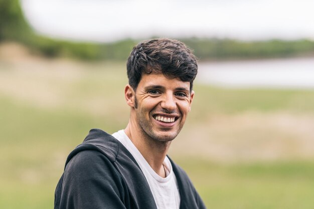 Retrato com foco seletivo em um homem caucasiano feliz sorridente com roupas esportivas em um parque