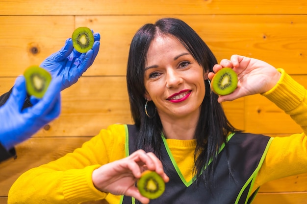 Retrato com muitos kiwis na mão de uma menina de frutas caucasiana morena