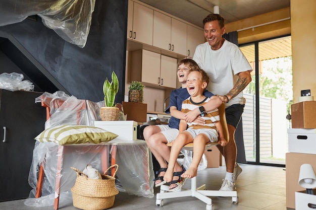 Foto retrato completo de familia feliz mudándose a una nueva casa con un padre despreocupado jugando con niños