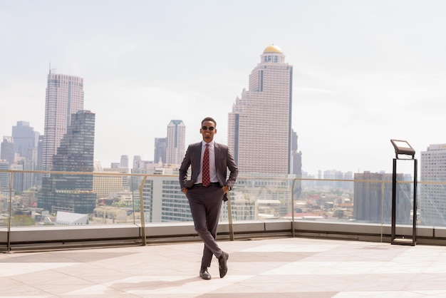 Retrato completo de un hombre de negocios africano con traje y corbata al aire libre en la ciudad mientras está de pie