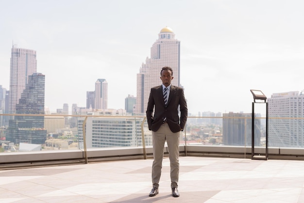 Retrato completo de un hombre de negocios africano con traje y corbata al aire libre en la ciudad mientras está de pie