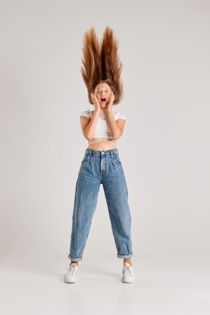 Retrato completo de una joven pelirroja con el pelo largo posando emocionalmente con ropa informal