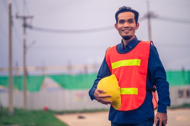 Retrato del concepto de construcción de ingeniero de hombre asiático Ingeniero de hombre asiático en el sitio de construcción Trabajador en el casco del trabajador del sitio de construcción trabajador de especificaciones de copia seguro en traje de seguridad en el trabajo