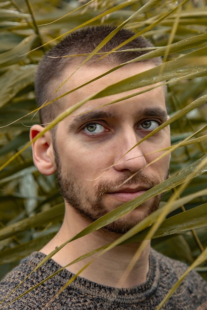 Retrato conceptual de un hombre en un montón de hojas Modelo de chico guapo posando entre los matorrales Primer plano