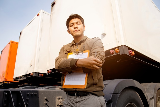 Foto retrato del conductor de camión asiático de pie con un camión remolque. lista de verificación de mantenimiento del vehículo de seguridad de inspección