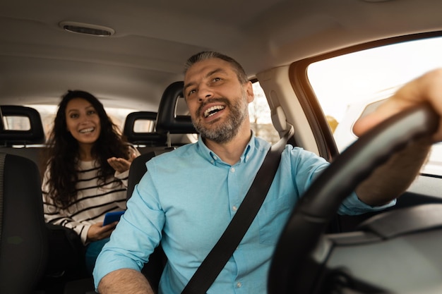 Foto retrato de un conductor masculino feliz montando un coche con un pasajero