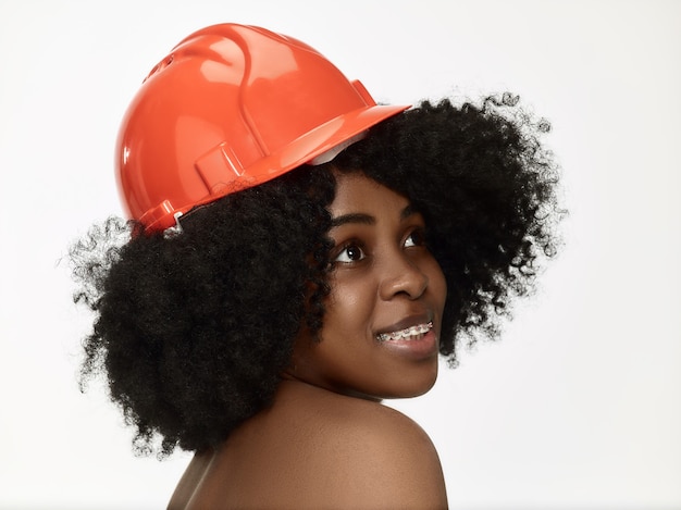 Retrato de confiada trabajadora en casco naranja