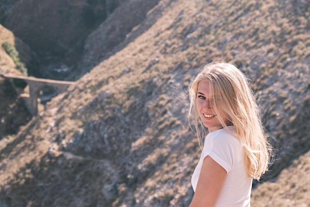 Retrato confiado joven alegre sonriente mujer rubia mira a la cámara contra el fondo