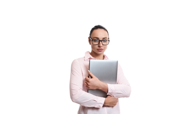 Retrato confiante de uma jovem mulher bonita vestindo roupas casuais de negócios, segurando um laptop nas mãos. Isolado no fundo branco com espaço de cópia,