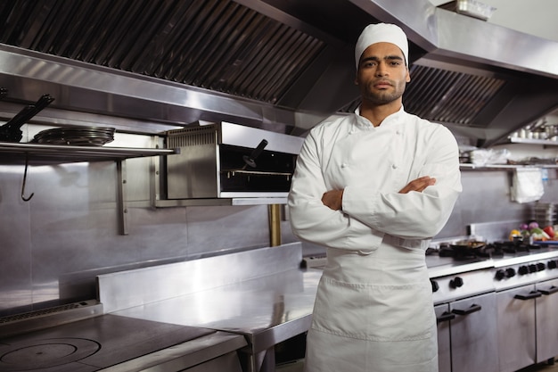 Retrato de confianza chef de pie con los brazos cruzados en la cocina comercial
