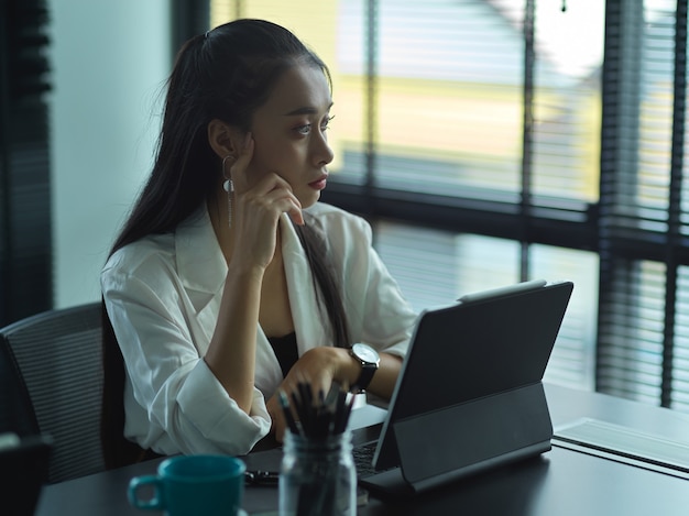 Retrato de confianza empresaria trabajando su estrategia mientras mira las ventanas