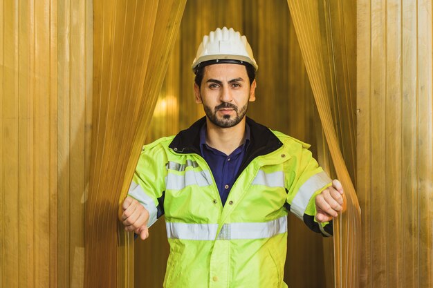 Retrato confianza guapo ingeniero latino trabajador hombre abriendo cortina de pvc amarillo en una fábrica de alimentos