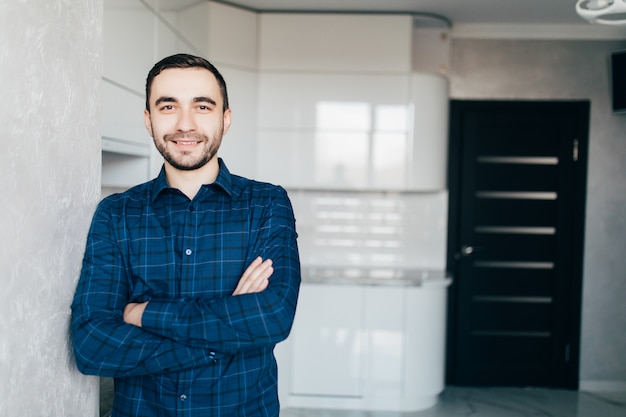 Retrato de confianza joven de pie junto a la cocina en casa