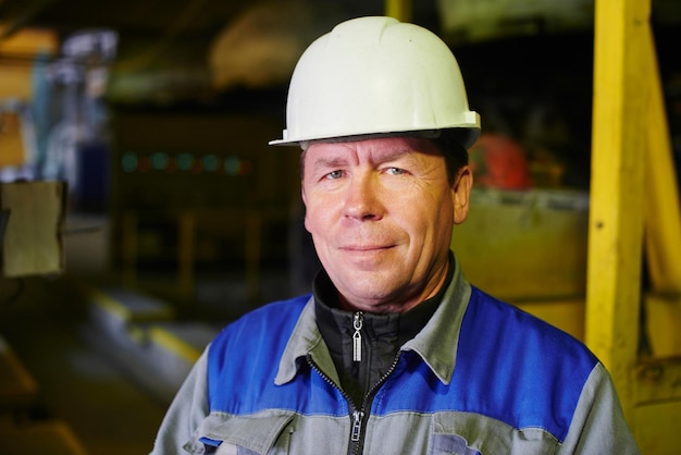 Retrato de un constructor con un mono y un casco en las instalaciones de la planta