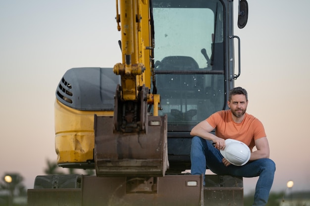 Retrato de constructor en un sitio de construcción Constructor con excavadora lista para construir una nueva casa Constructor de construcción usa uniforme de construcción en camión de excavación construcción de constructor de excavación