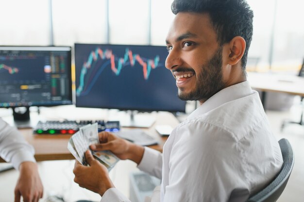 Retrato de un corredor del mercado de valores indio o árabe con éxito positivo Gráficos criptográficos en la pantalla de un portátil