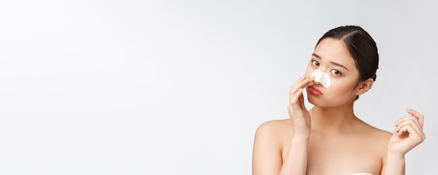 Retrato de cosmetología de hermosa modelo asiática femenina con máscara en la nariz Primer plano de mujer joven sana con piel suave pura y maquillaje natural fresco