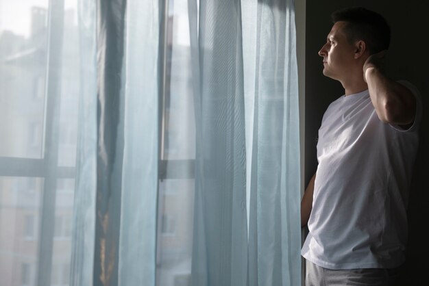 Foto retrato creativo del hombre con cortinas y sombras desde la ventana.