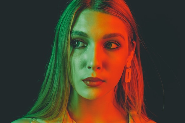 Retrato criativo de um close-up da bela modelo feminino. iluminação laranja e verde no estúdio.