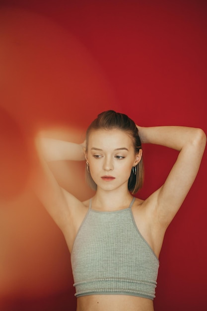 Retrato criativo de uma linda garota em um fundo vermelho olhando para longe com uma cara séria Senhora de camiseta cinza isolado reflexo amarelo na foto Linda garota em um fundo colorido