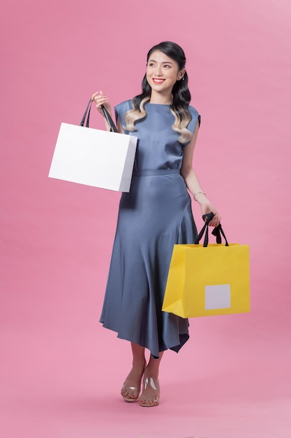 Retrato de cuerpo completo de hermosa mujer feliz con bolsas aisladas en rosa Concepto de compras