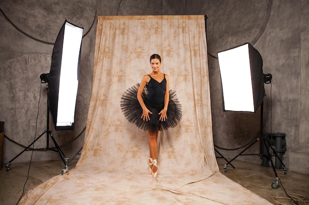 Foto retrato de cuerpo completo una joven bailarina en un traje de baile negro está posando en un estudio oscuro